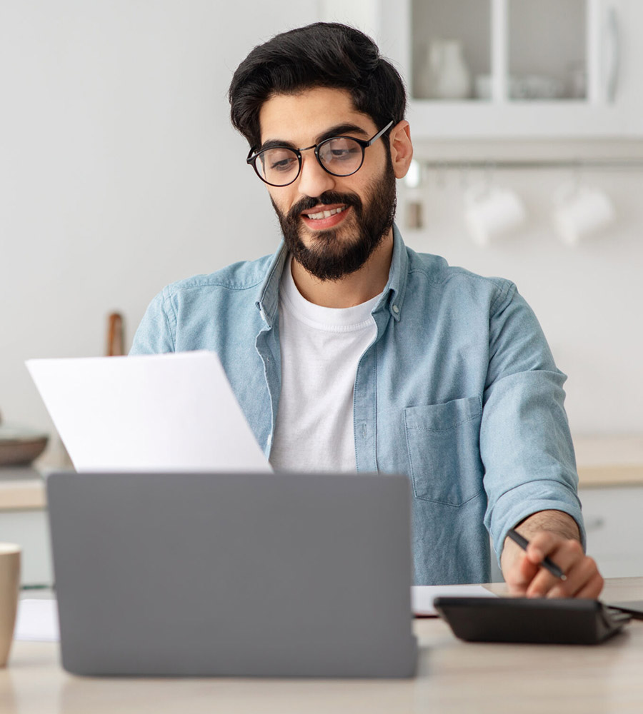 Happy Arab man reading document and looking at laptop