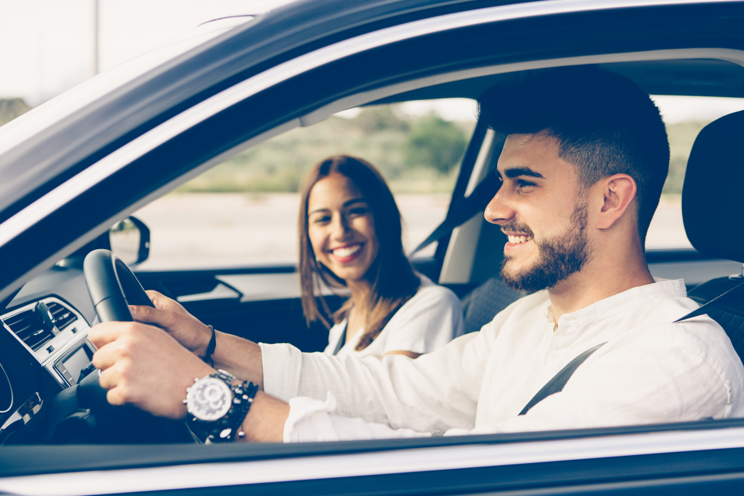 Profile of a happy man driving a car and woman sitting in passenger seat smiling