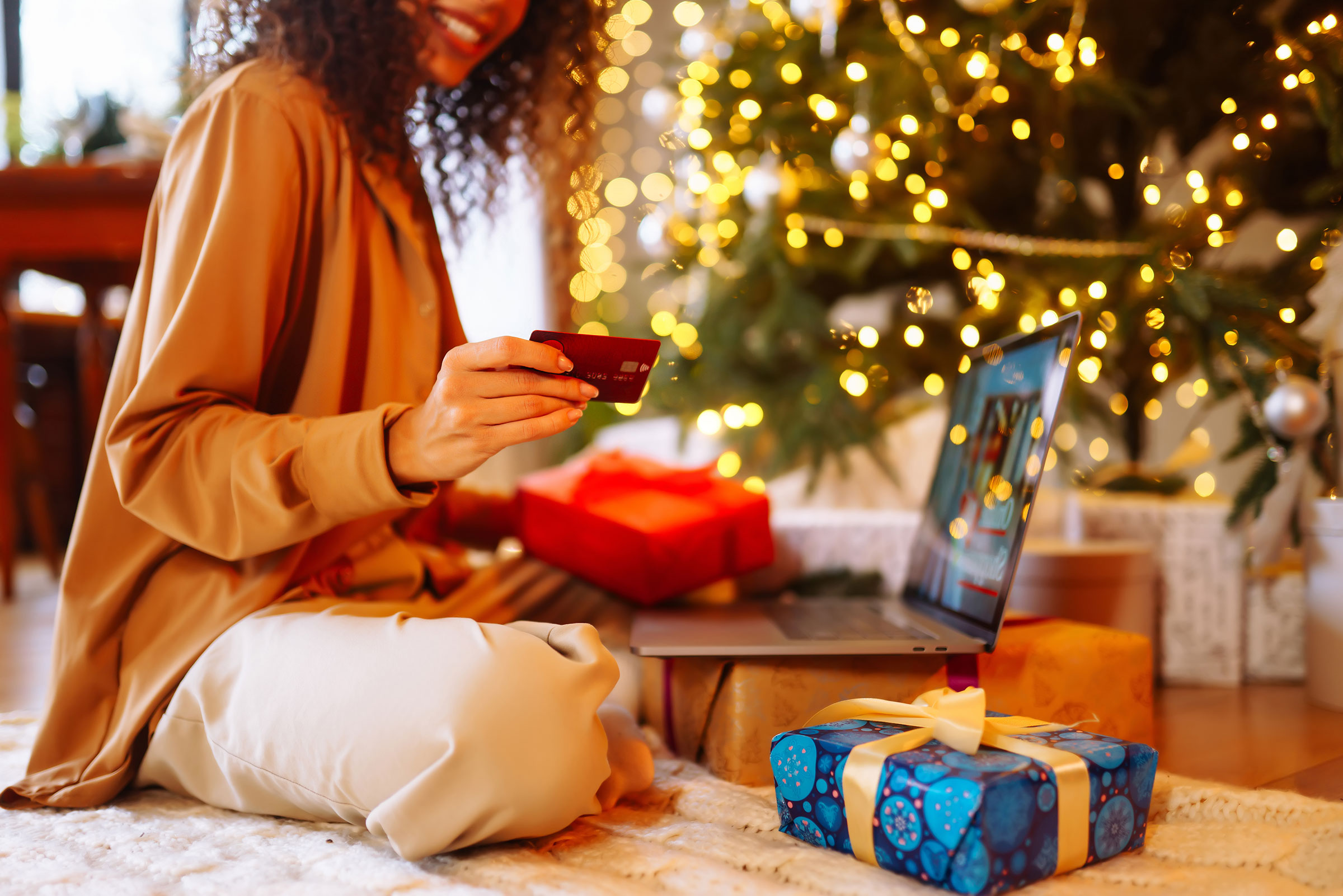 Woman next to Christmas tree uses credit card to shop online