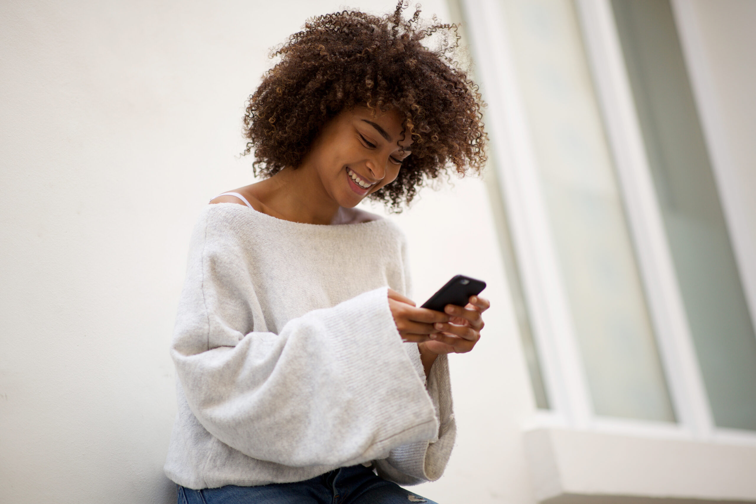 Portrait smiling young African american woman looking at mobile phone