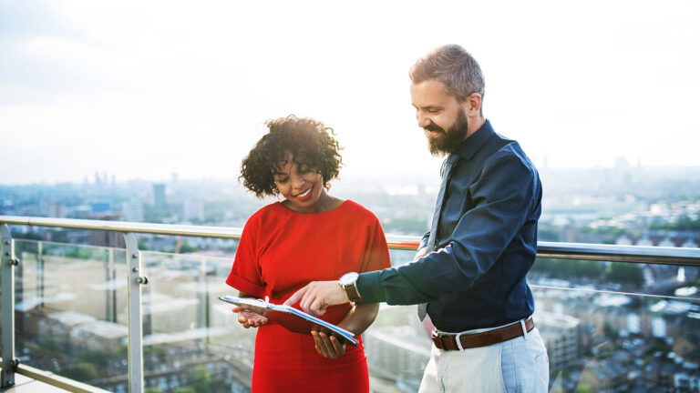 Two business people on balcony reviewing documents