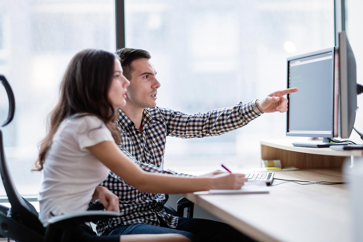 Two young business colleagues working on computer