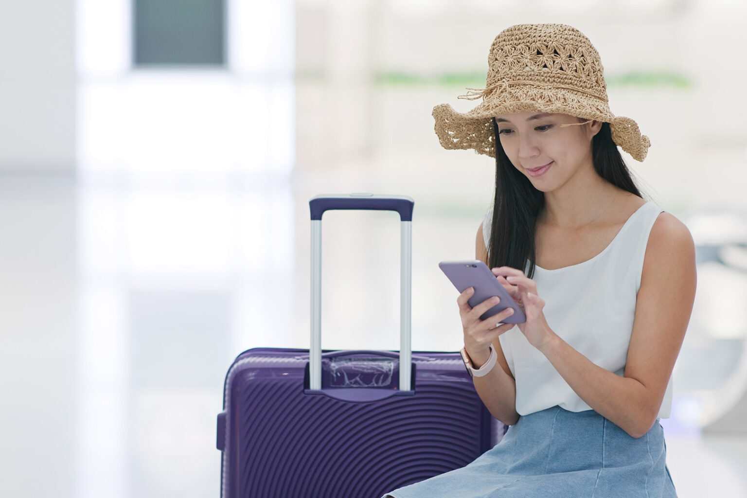 Asian woman traveling and using her phone at the airport