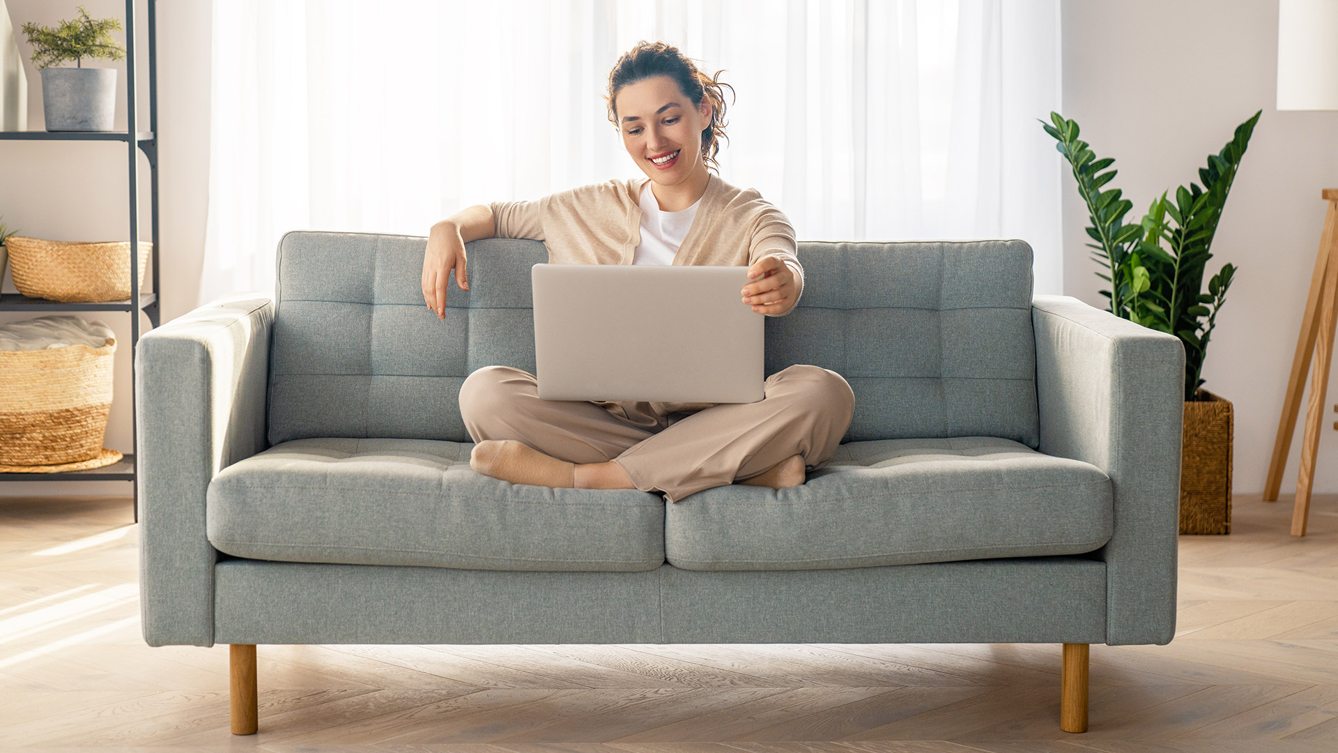 Woman uses laptop at home on the couch