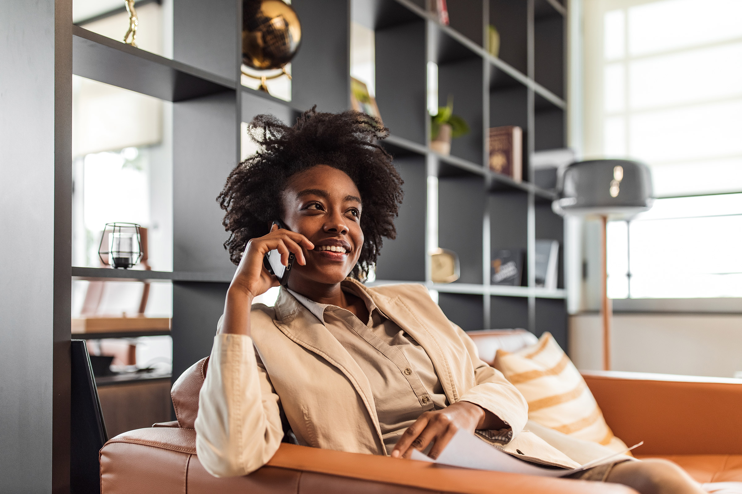 Woman smiling while talking on phone in a stylish interior.