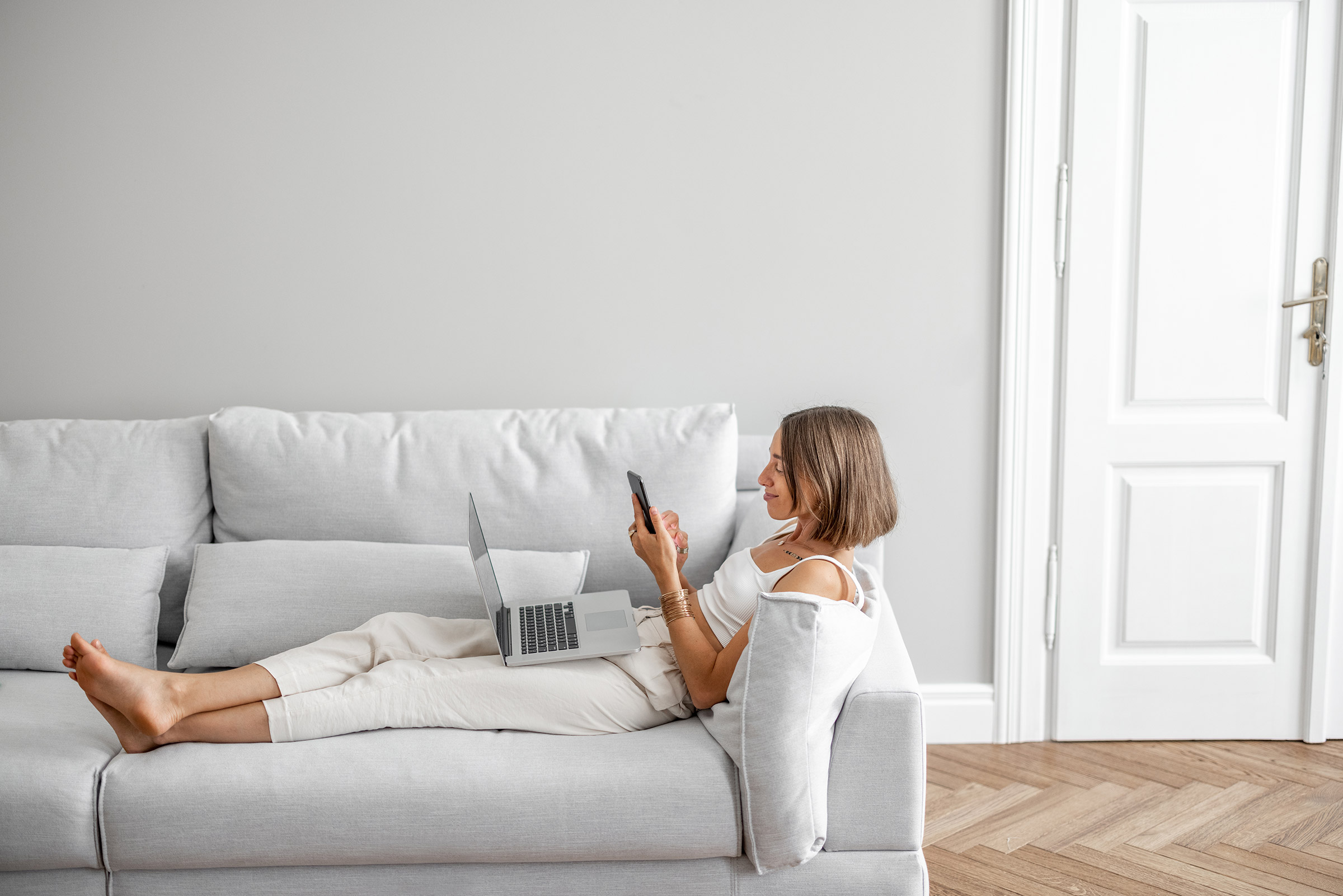 Woman relaxing on couch with laptop and phone
