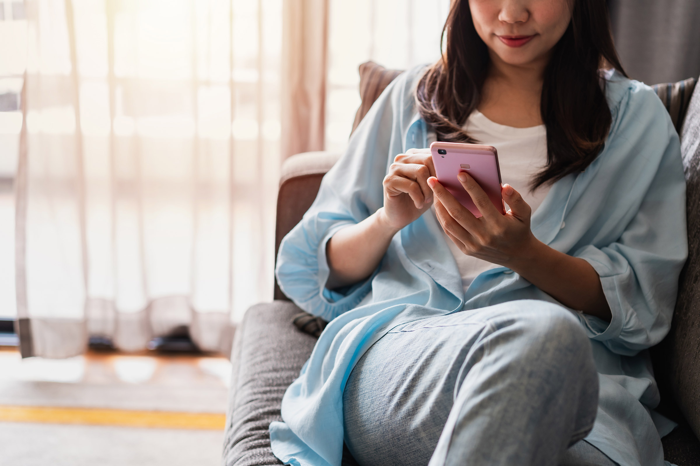 Young woman relaxing on the couch using her phone