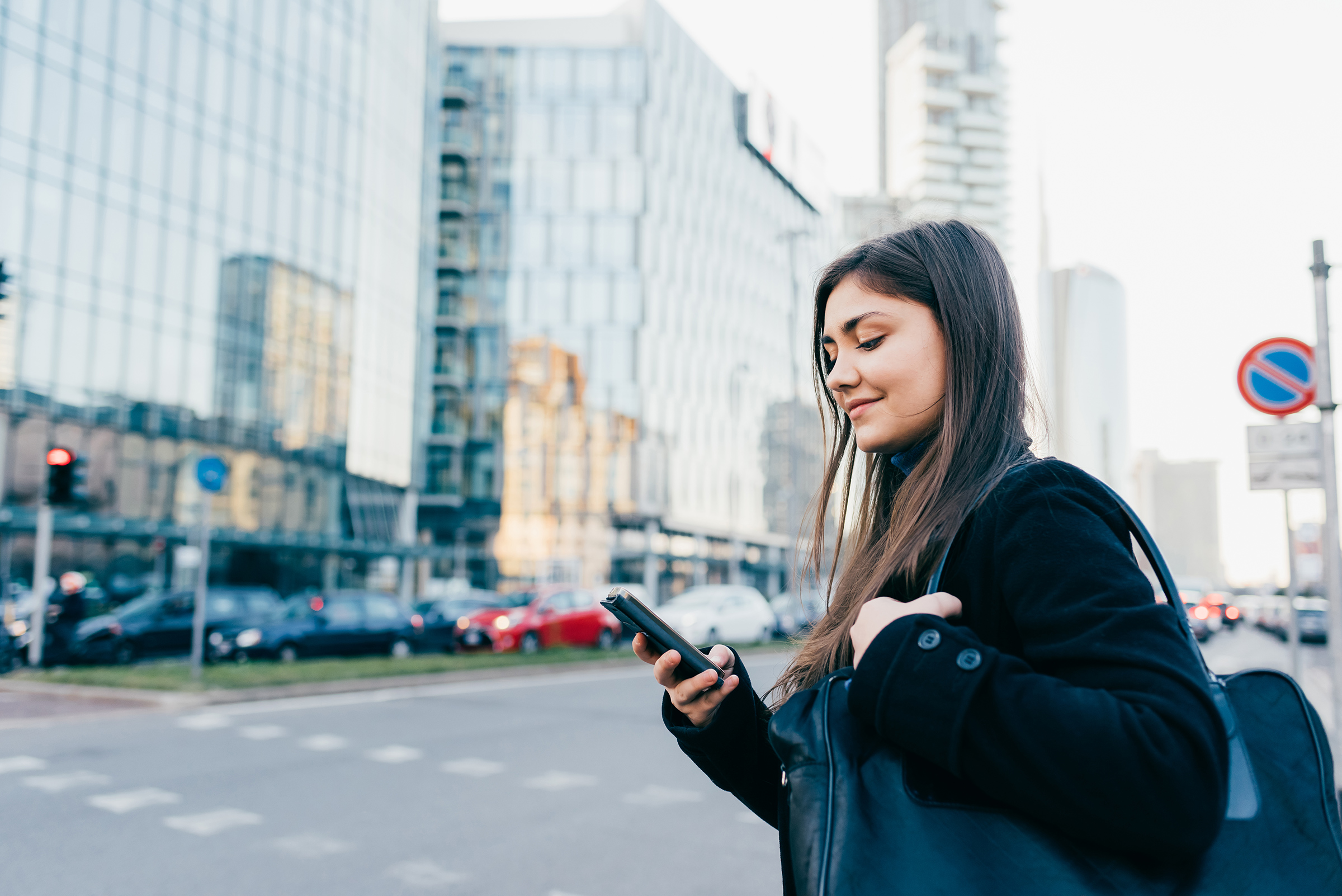 young woman using smart phone while walking through the city